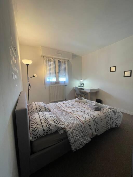 a bedroom with a bed and a table and a window at APPARTEMENT COSY Balcon à 30min de PARIS in Cergy