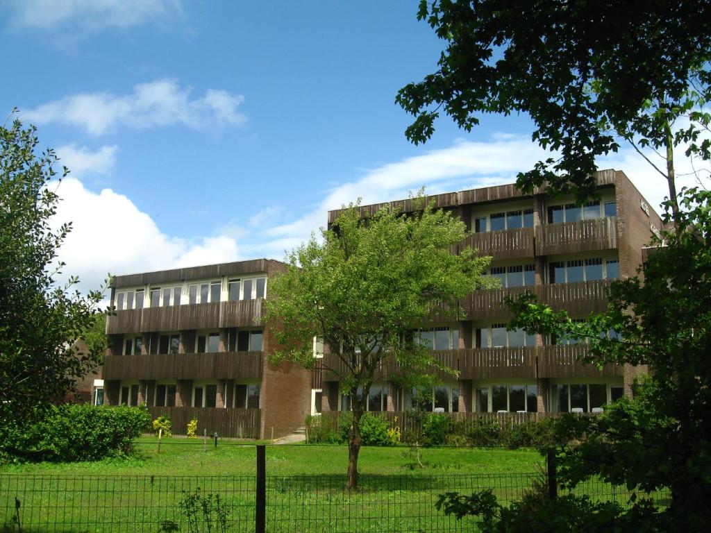 een gebouw met een boom ervoor bij Hotel Hofker in Nes