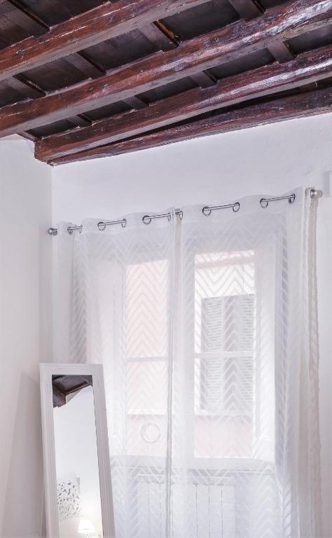 espejo frente a una ventana con cortinas en Stranamore Apartments Trastevere, en Roma