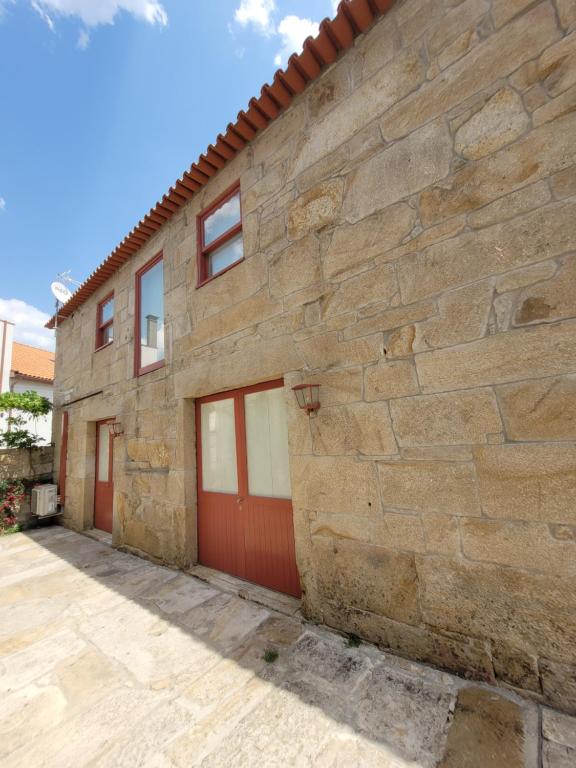 a stone house with red doors and a stone wall at Alijó Douro House in Alijó