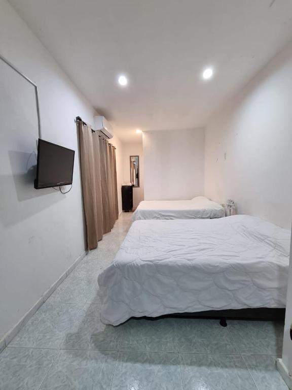 a bedroom with two beds and a flat screen tv at Apartaestudio Maria in Cartagena de Indias