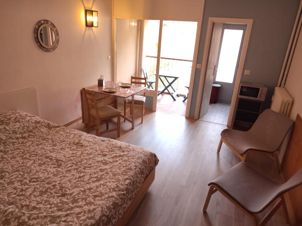 une chambre d'hôtel avec un lit, une table et des chaises dans l'établissement Studio Soleil Vernet, à Vernet-les-Bains