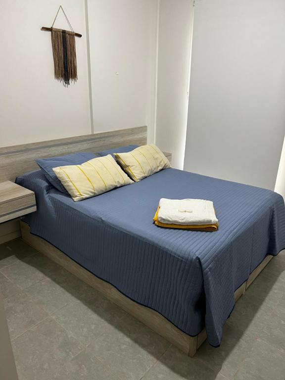 een bed met blauwe lakens en gele kussens in een kamer bij Talavera 480 in Salta
