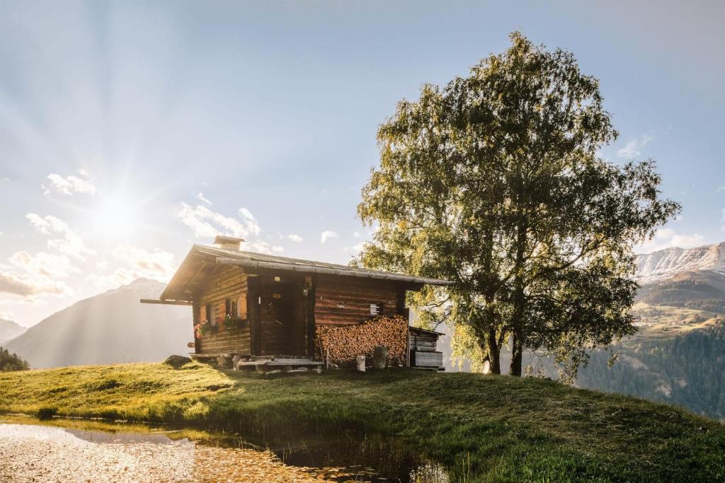 eine Blockhütte auf einem Hügel mit einem Baum in der Unterkunft Weiherhütte Ried in Ried im Oberinntal