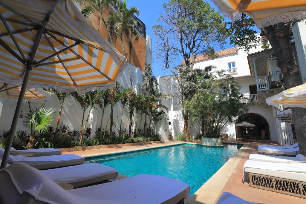 una piscina con sillas y sombrillas junto a un edificio en Casa Pestagua Relais Châteaux, en Cartagena de Indias