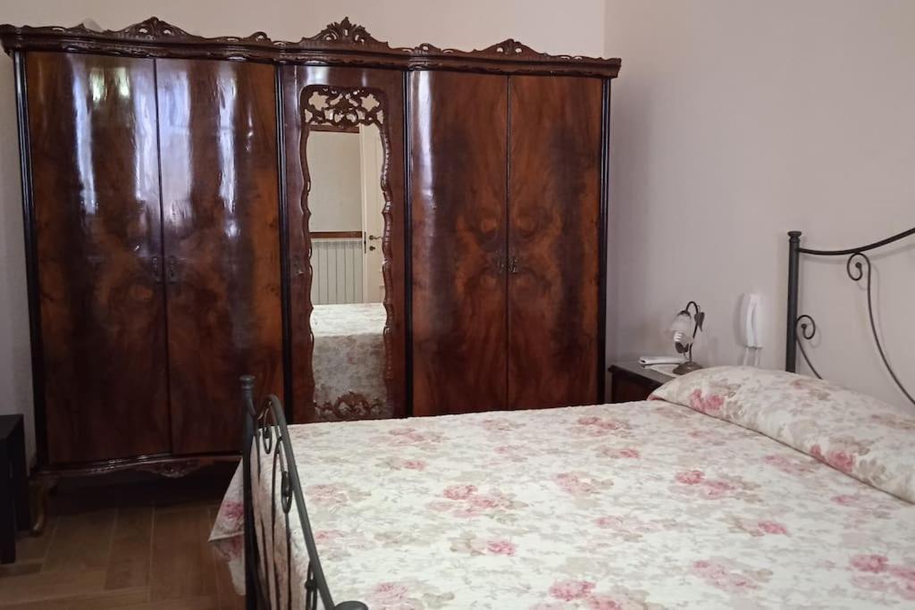 a bedroom with a bed and a large wooden cabinet at Casa Sofia: comodi e tranquilli in Maruggio