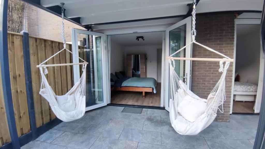 two hanging hammocks on a porch with a bedroom at B&B Sabai Sabai Amsterdam in Amsterdam