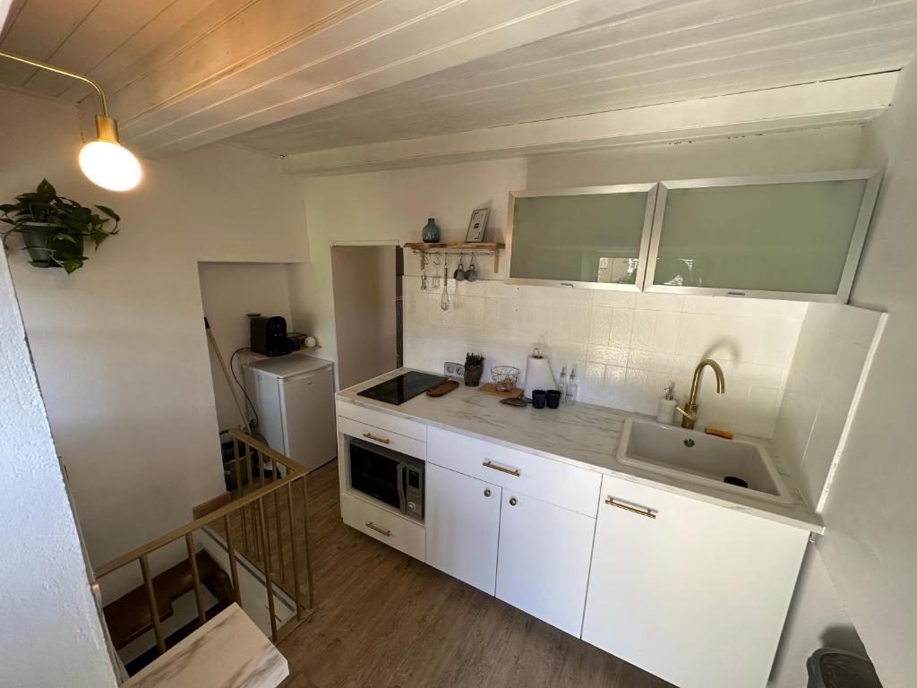 a kitchen with white cabinets and a sink at T1 charmant et typique sur les hauteurs de Bastia in Bastia