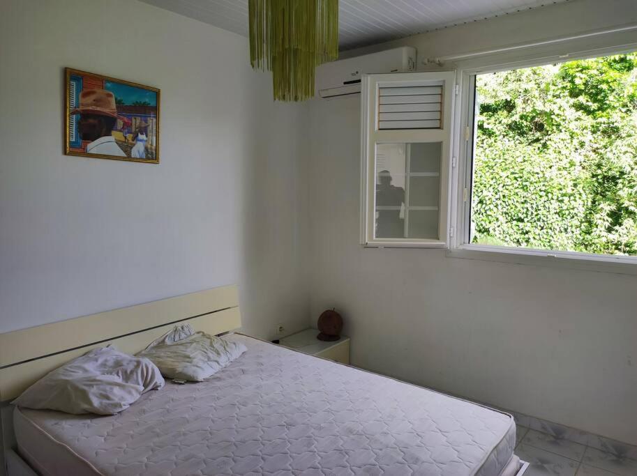 een witte slaapkamer met een bed en een raam bij Villa familiale avec piscine in Le Marin