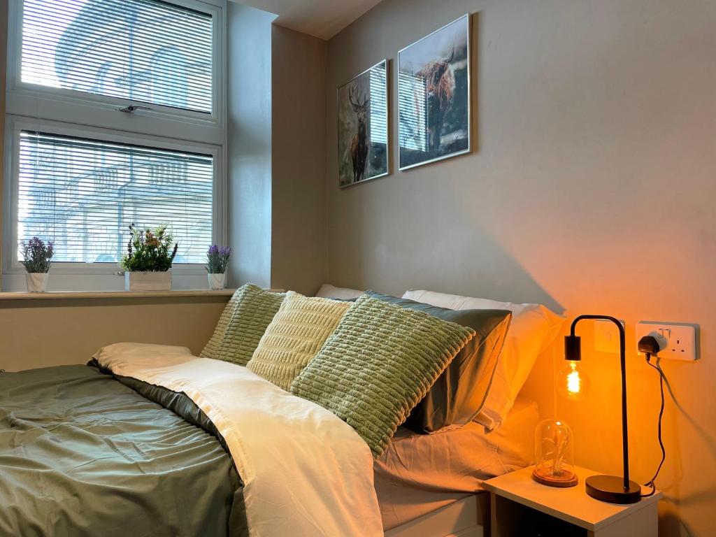 a bedroom with a bed and a lamp and two windows at Natural Studio by HNFC Stays in Newcastle upon Tyne