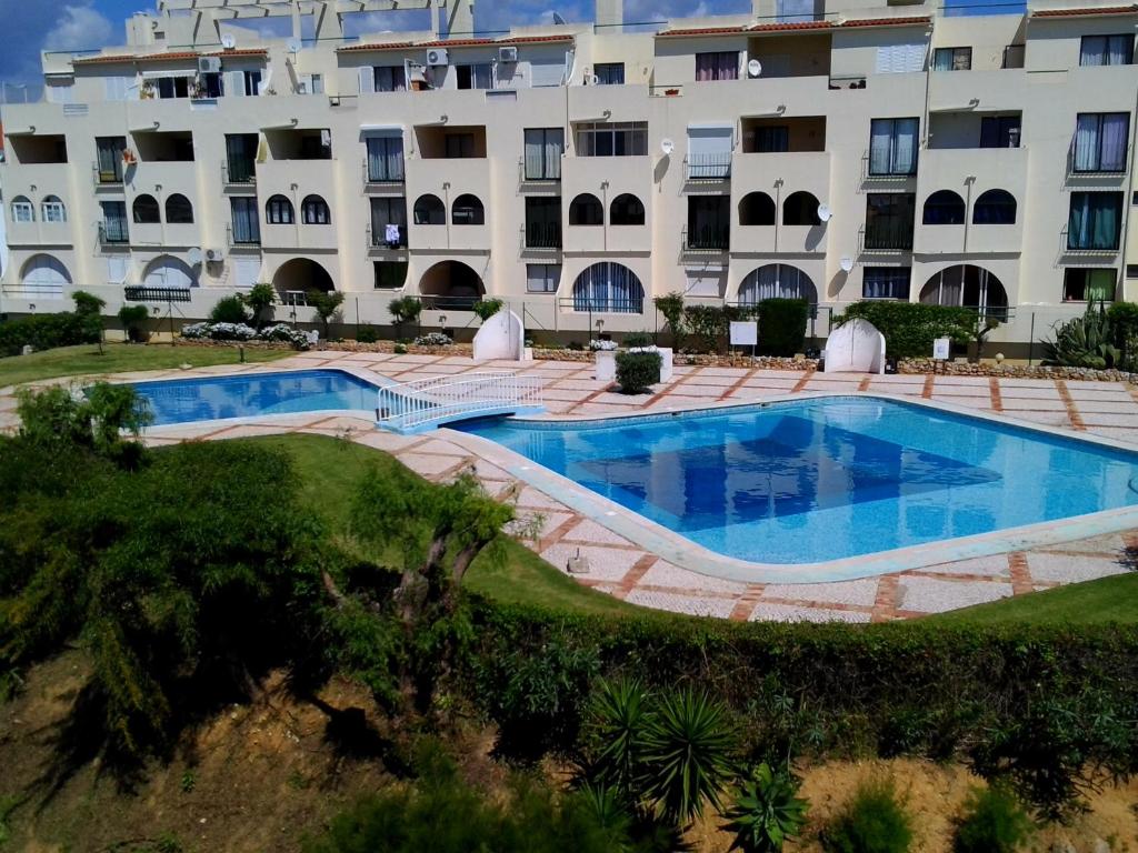 um grande edifício com uma piscina em frente em Apartamentos Poente da Aldeia em Albufeira