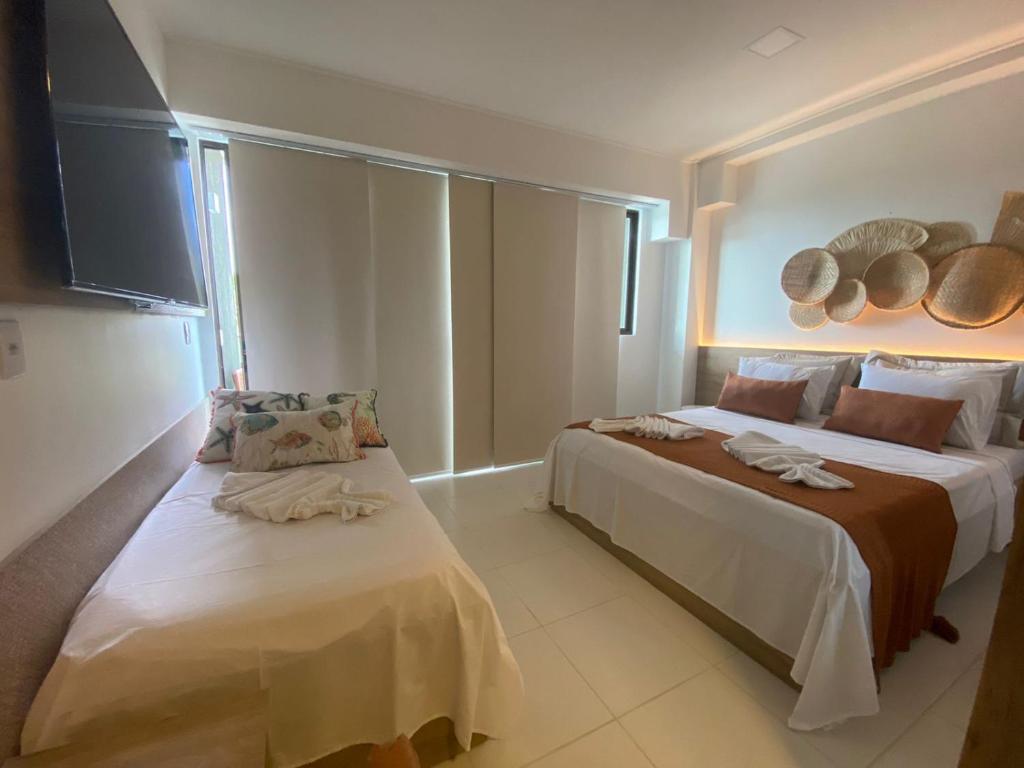 a bedroom with two beds and a flat screen tv at Mana Beach Flat Prime in Ipojuca