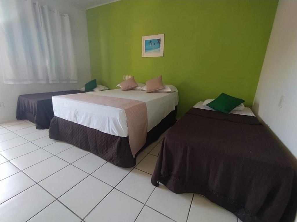 2 camas en una habitación con paredes verdes en Pousada Água de Côco, en Prado