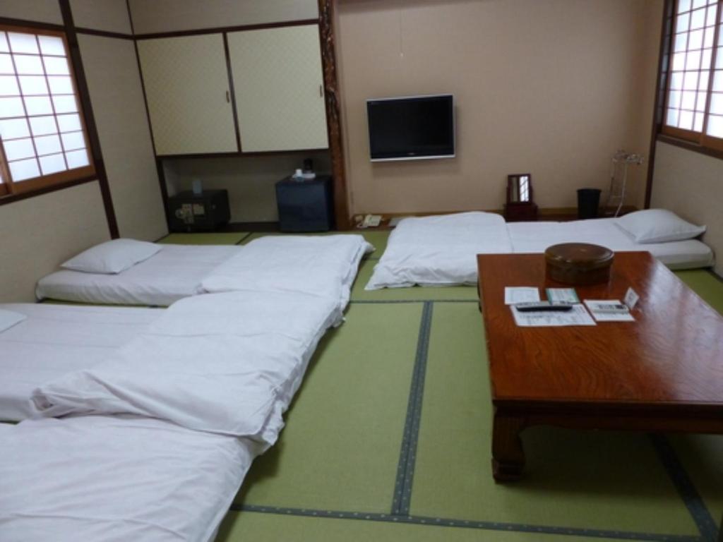 Habitación con 4 camas, mesa y mesa. en Minshuku Kuwataniya - Vacation STAY 96491v en Takayama