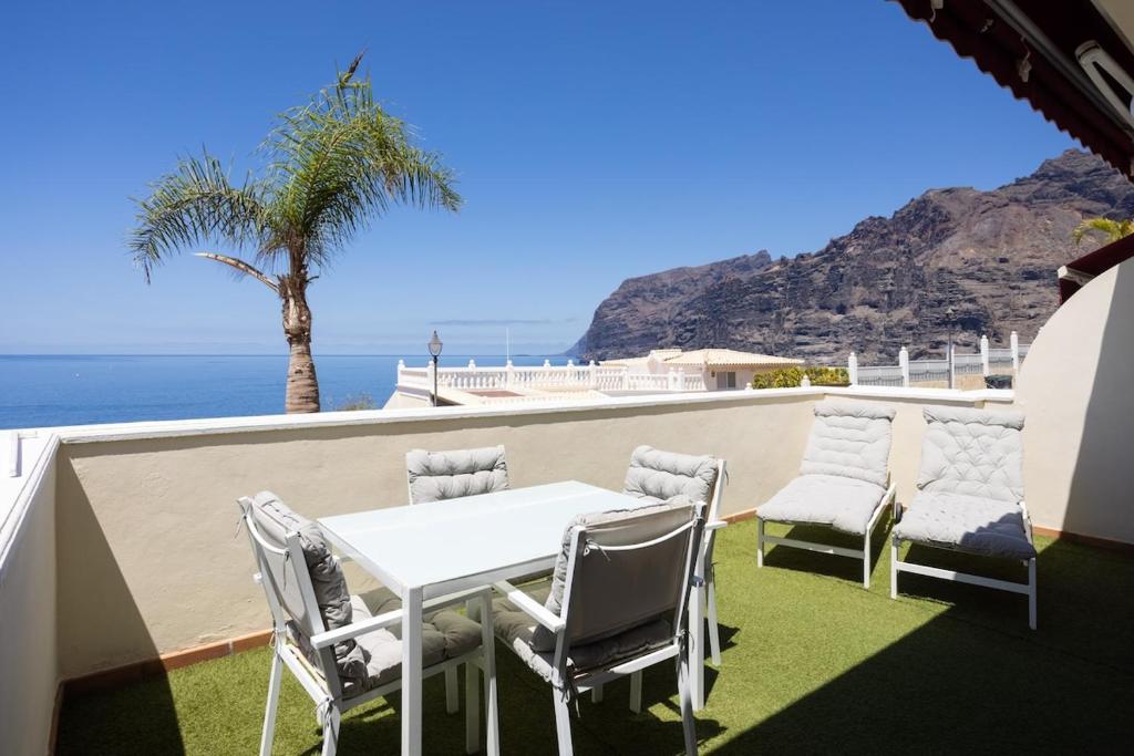 - une table et des chaises blanches sur un balcon donnant sur l'océan dans l'établissement EDEN RENTALS Hermosas Vistas al Océano y Los Acantilados, à Acantilado de los Gigantes