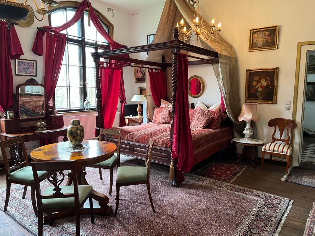 1 dormitorio con cama con dosel y mesa en Park Villa Reichenbach, en Reichenbach