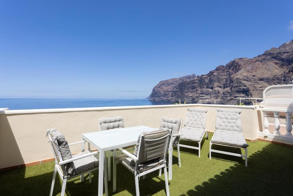 - une table et des chaises blanches sur un balcon donnant sur l'océan dans l'établissement EDEN RENTALS Fabulosas Vistas al Mar y Los Acantilados, à Acantilado de los Gigantes