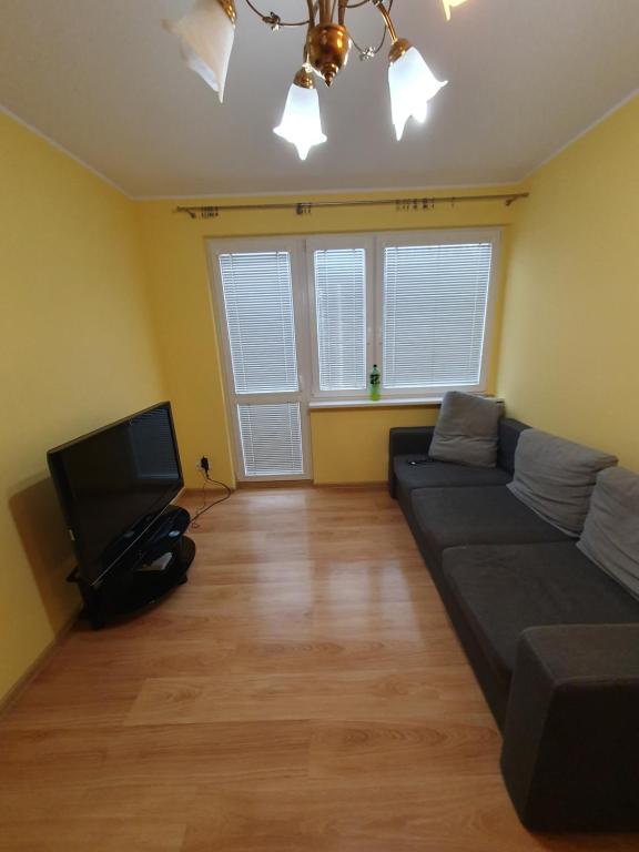uma sala de estar com um sofá e uma televisão de ecrã plano em Legionów Apartament em Konin
