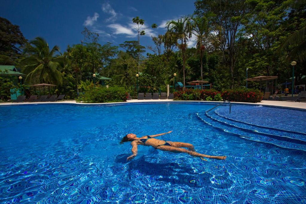 Manzanillo Caribbean Resort في بويرتو فيجو: وجود امرأة مستلقية في مسبح في منتجع