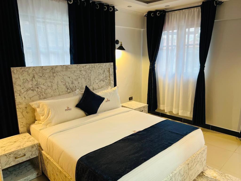 Schlafzimmer mit einem großen Bett und schwarzen Vorhängen in der Unterkunft SR Apartments Milimani, Kisumu in Kisumu