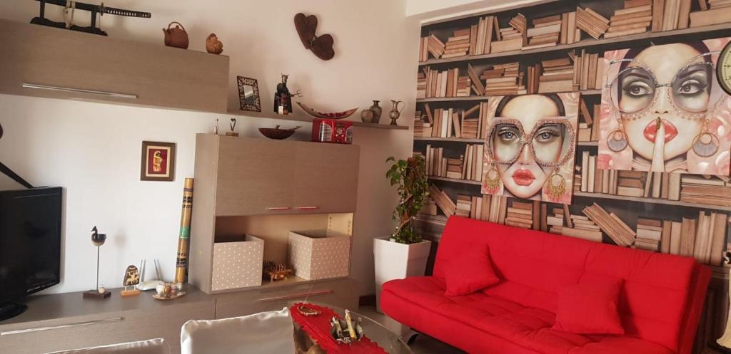 a living room with a red couch and a wall with faces at Alice nel paese delle meraviglie 