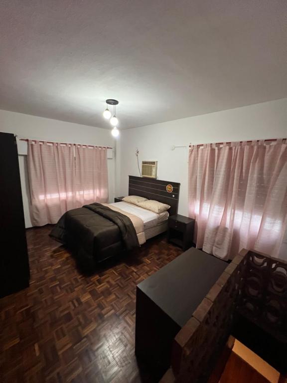 a bedroom with a bed and a couch and curtains at El pasillo Centro in Rosario