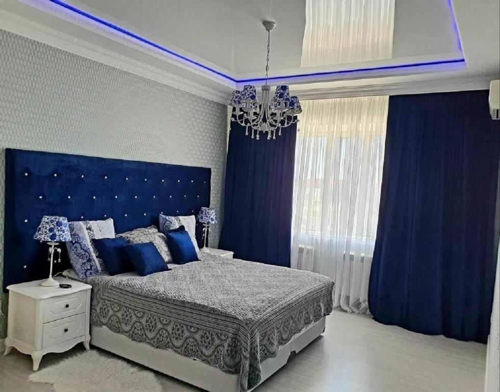 Schlafzimmer mit blauen Vorhängen und einem Bett mit blauem Kopfteil in der Unterkunft Апартаменты 2 комнатная возле теннисного центра in Aqtöbe