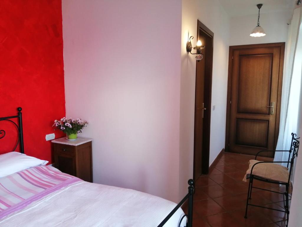 1 dormitorio con cama y pared roja en Agriturismo La Pagliarella, en Caramanico Terme