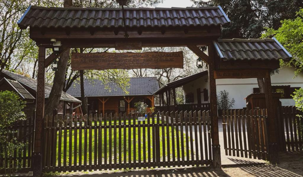 a wooden gate with a fence in front of a house at Vándor tanya in Ágasegyháza