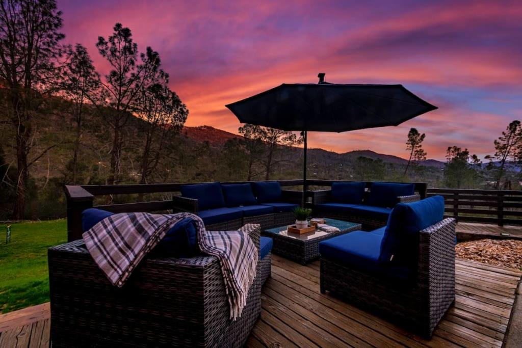 un patio con sofás y una sombrilla en una terraza en Sierra Vista Lookout Lodge with Creek, Waterfall and Waterholes, minutes from Bass Lake and Yosemite South Gate, en North Fork