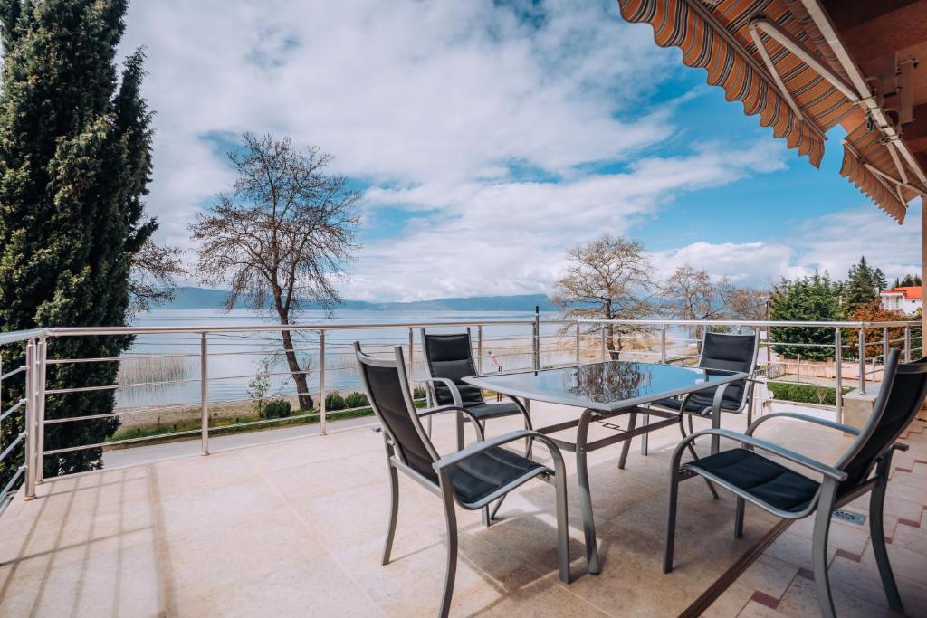 een patio met een tafel en stoelen en uitzicht op het water bij VILLA AFRODITA LAKE SIDE in Lagadin