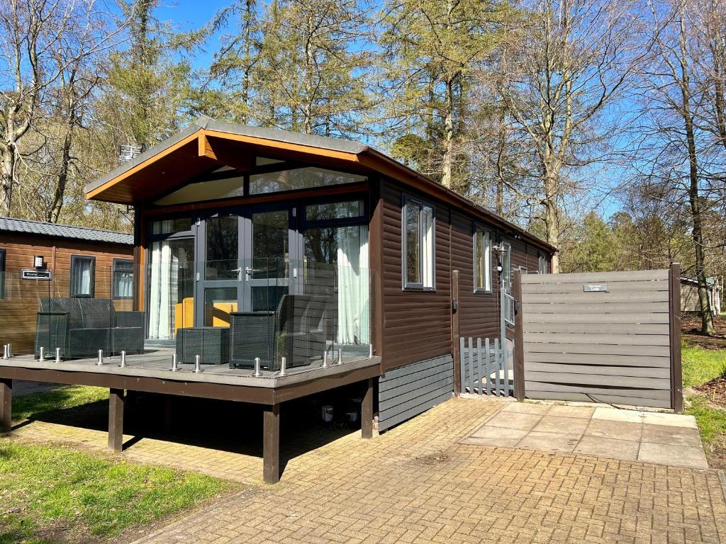 a small cabin with a large deck in the yard at Barnston Lodge in Newton on the Moor