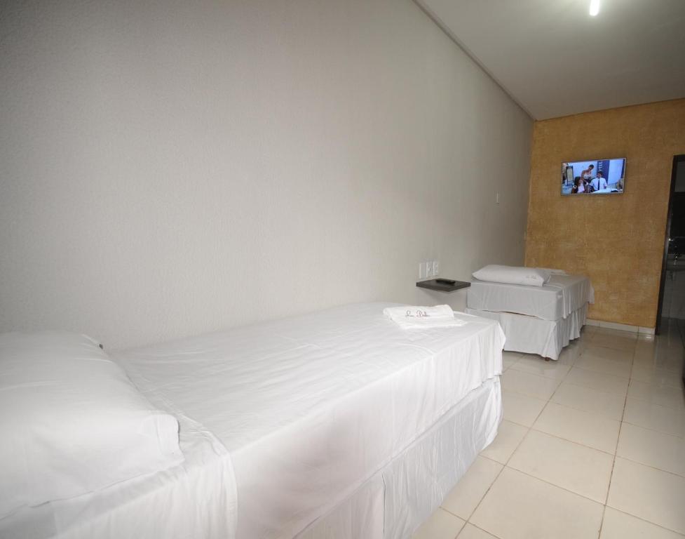 a bedroom with two beds and a tv on the wall at La Bella Hotel in Imperatriz