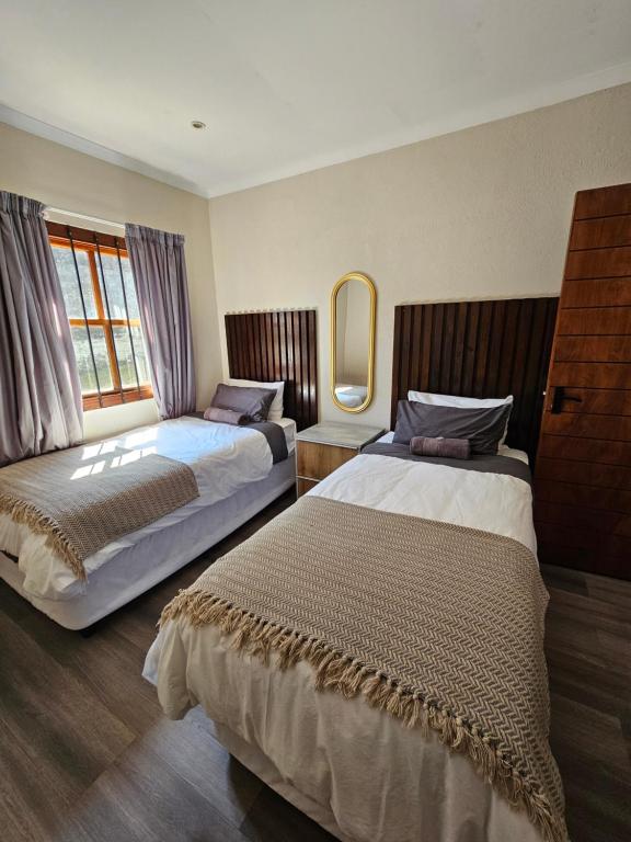 a hotel room with two beds and a mirror at Pine View Guesthouse Graskop in Graskop
