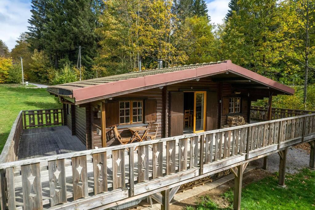 une cabane en bois sur un pont avec un porche dans l'établissement Agréable chalet cocooning en lisière de forêt, à Champdray