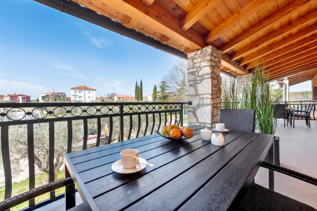 a wooden table with a bowl of fruit on a balcony at Comfort Apartments Karla in Rovinj