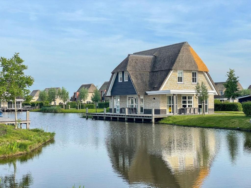 een huis met een gambrel dak op een rivier bij Spacious villa with two saunas, on the Tjeukemeer in Delfstrahuizen