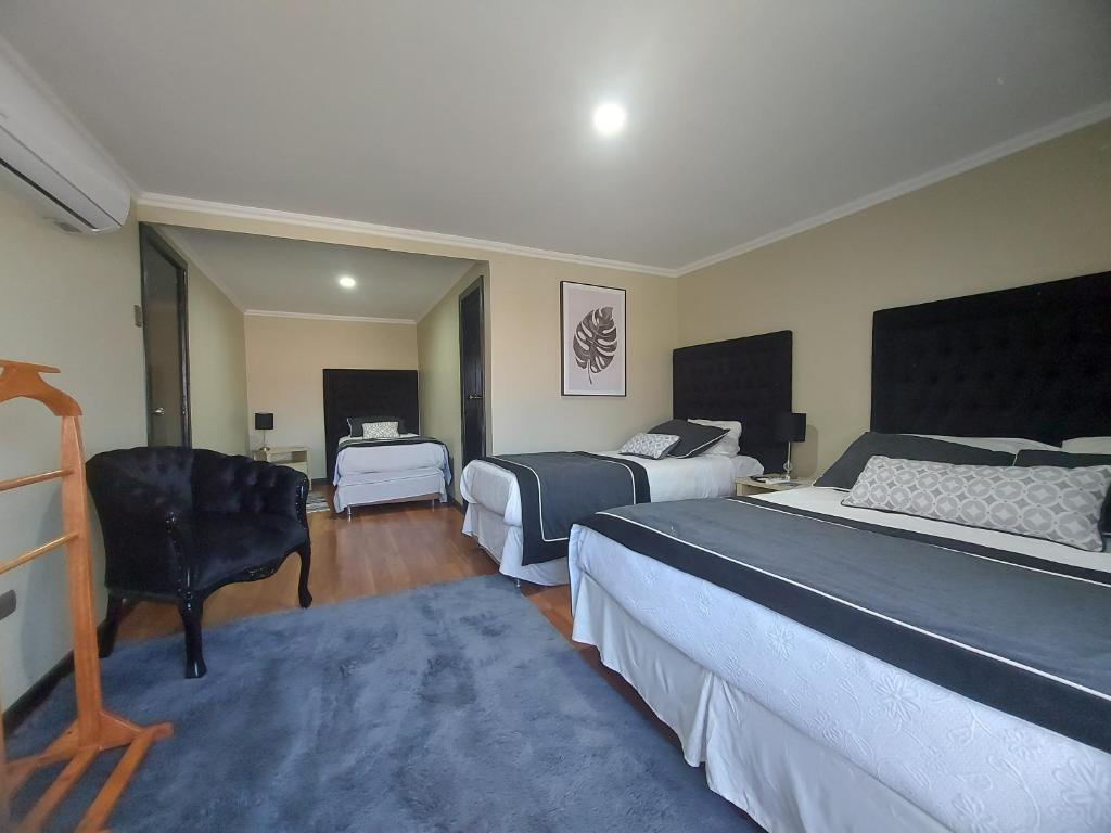 ein Hotelzimmer mit 2 Betten und einem Stuhl in der Unterkunft Hotel Rarinco in Los Ángeles