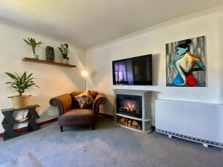 a living room with a chair and a fireplace at Apartment with parking, close to the Raigmore hospital in Inverness