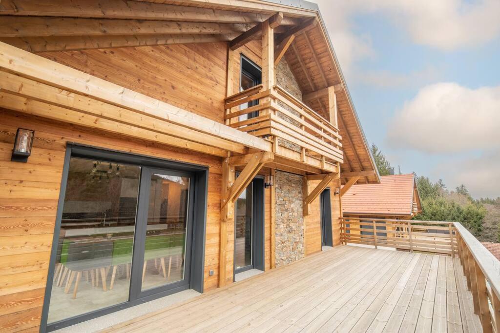 drewniany dom z balkonem ze szklanymi drzwiami w obiekcie L'orée des bois, SPA et Sauna w mieście Gerbépal