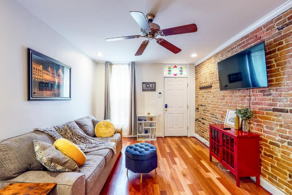 a living room with a couch and a brick wall at The Trailblazing Tribble House of Federal Hill in Baltimore