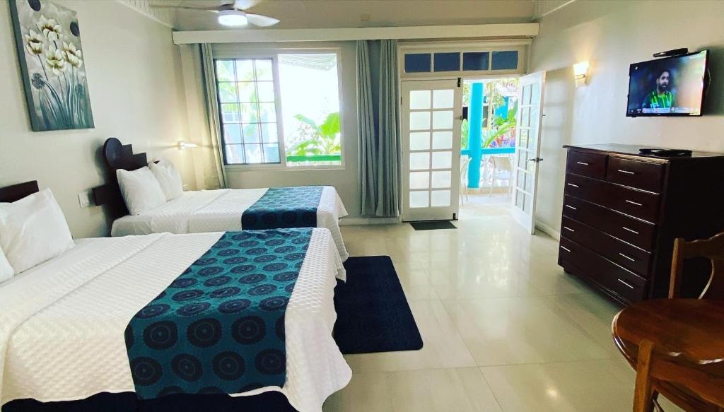 um quarto de hotel com duas camas e uma televisão em THE BOARDWALK VILLAGE em Negril