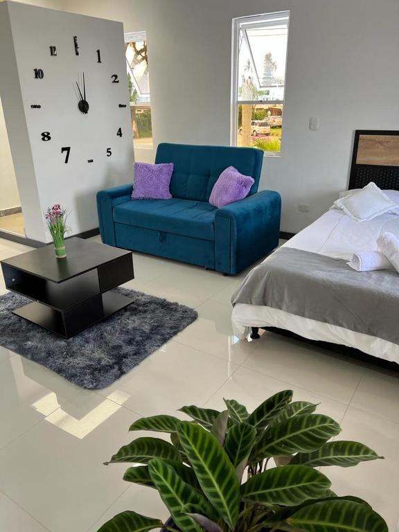 a living room with a blue couch and a clock at apartaestudios las astromelias Armenia in Armenia