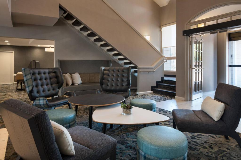 eine Lobby mit Stühlen, Tischen und einer Treppe in der Unterkunft Residence Inn San Ramon in San Ramon