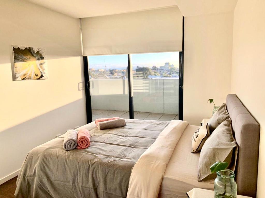a bedroom with a large bed with a large window at Shared Homestay Tranquil Art Deco Private Room with Private Bathroom In Brunswick in Melbourne