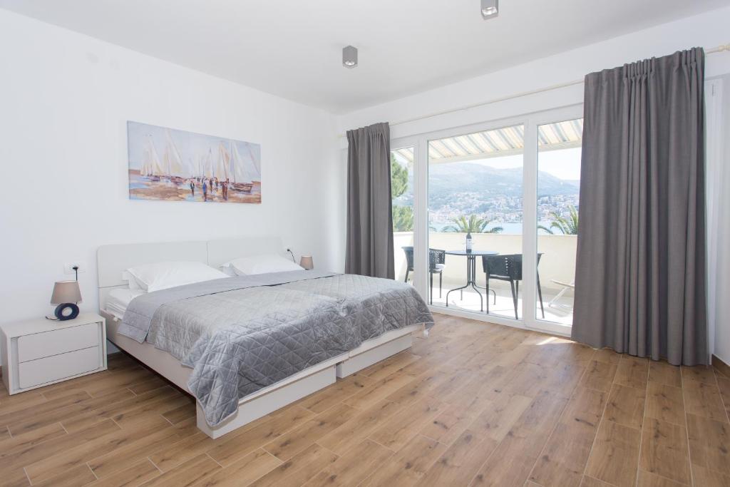 Dormitorio blanco con cama y ventana grande en Apartman Stobreč en Split