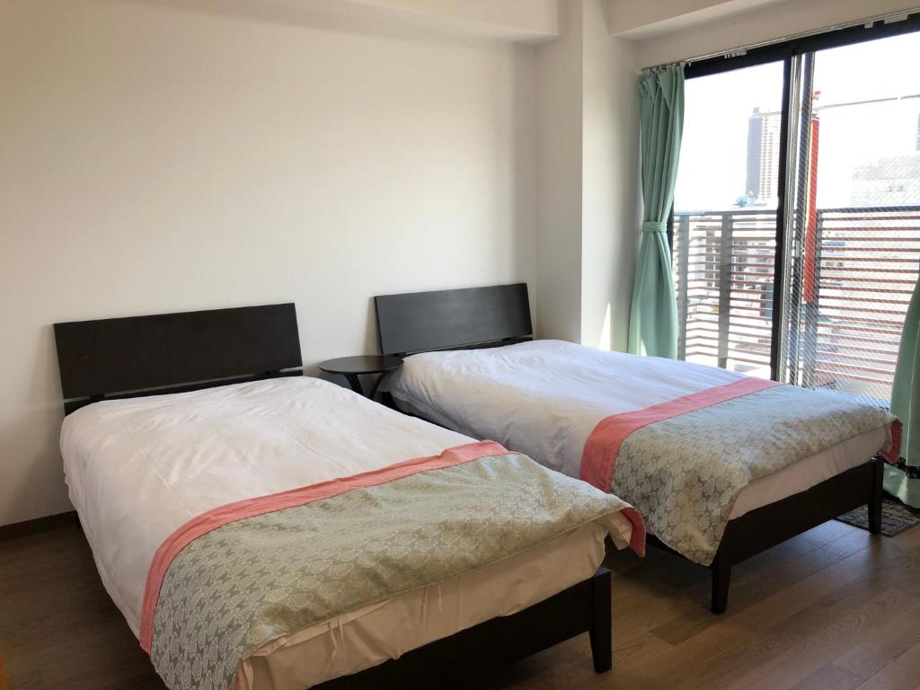 two beds in a room with a window at 安ホテルサンシャイン in Tokyo