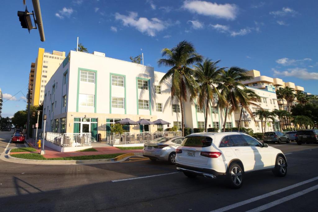 um carro branco dirigindo por uma rua ao lado de um edifício em Venezia em Miami Beach