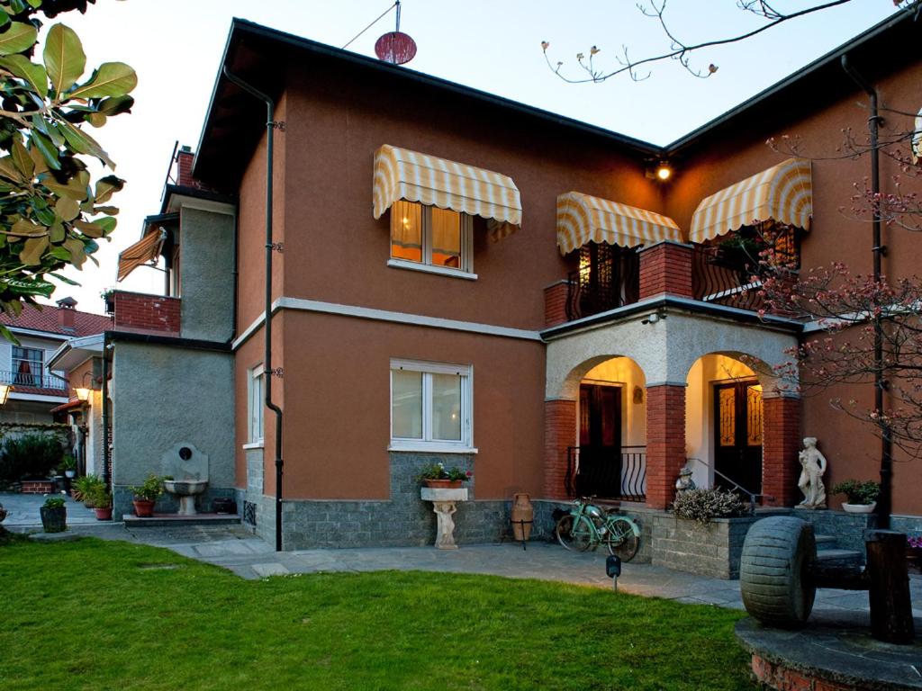 una casa roja con césped delante en Le Coccinelle B&B, en Grignasco