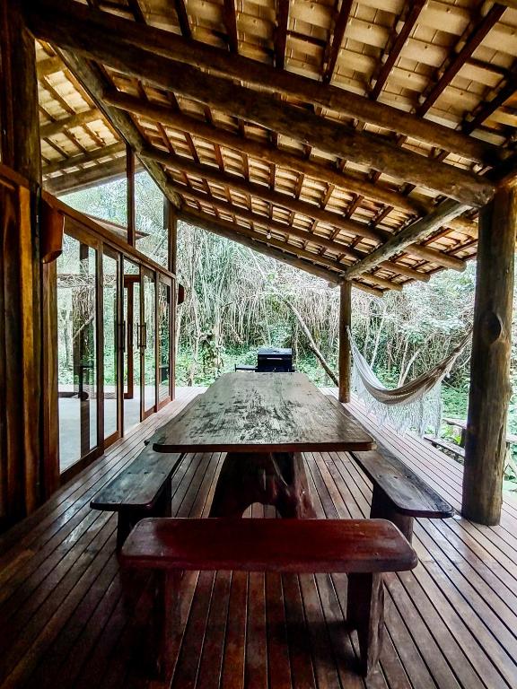 a wooden table on a wooden deck with a bench at Vila Floresta - Chalé Pato Mergulhão in Alto Paraíso de Goiás